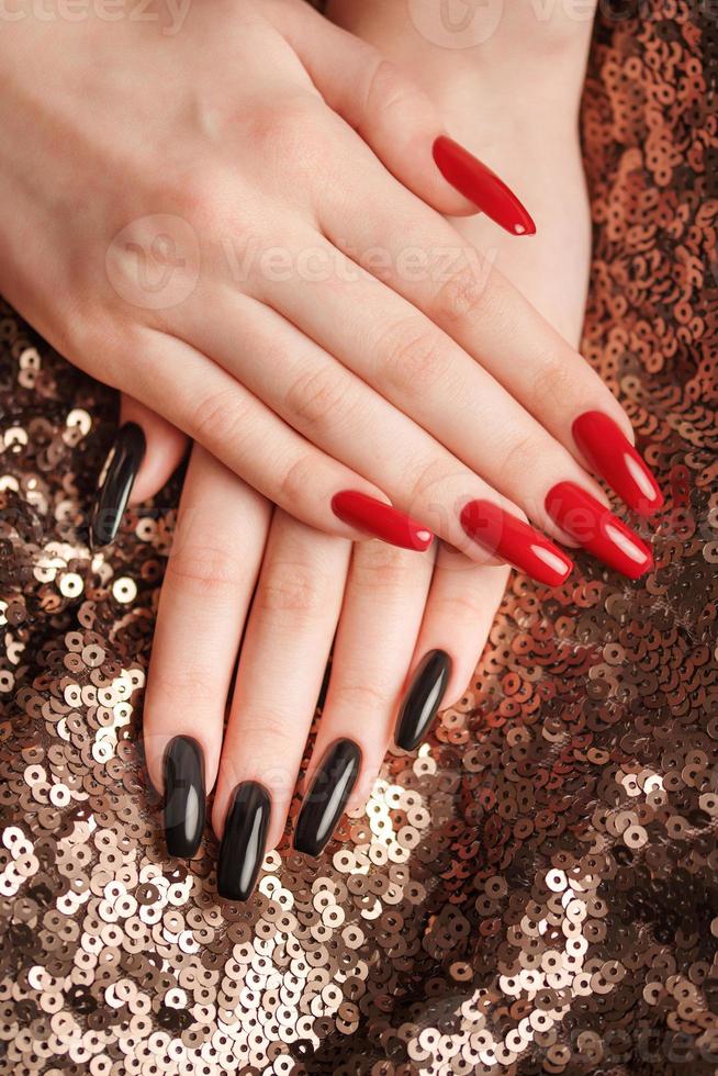 manos de una joven con manicura roja y negra en las uñas foto