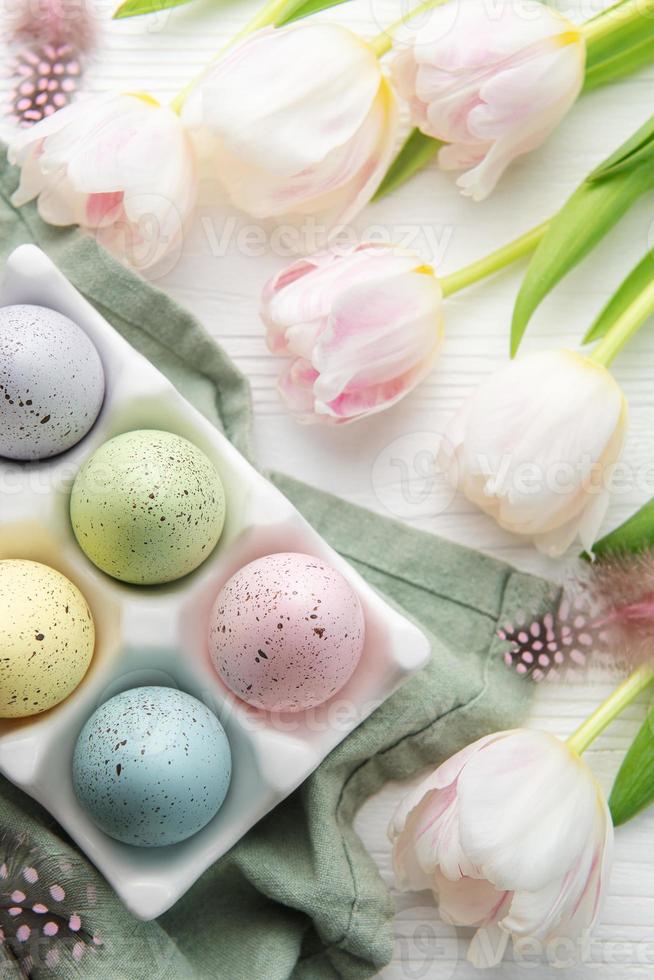 Holder with Easter eggs painted pastel colors on a white wooden background. photo