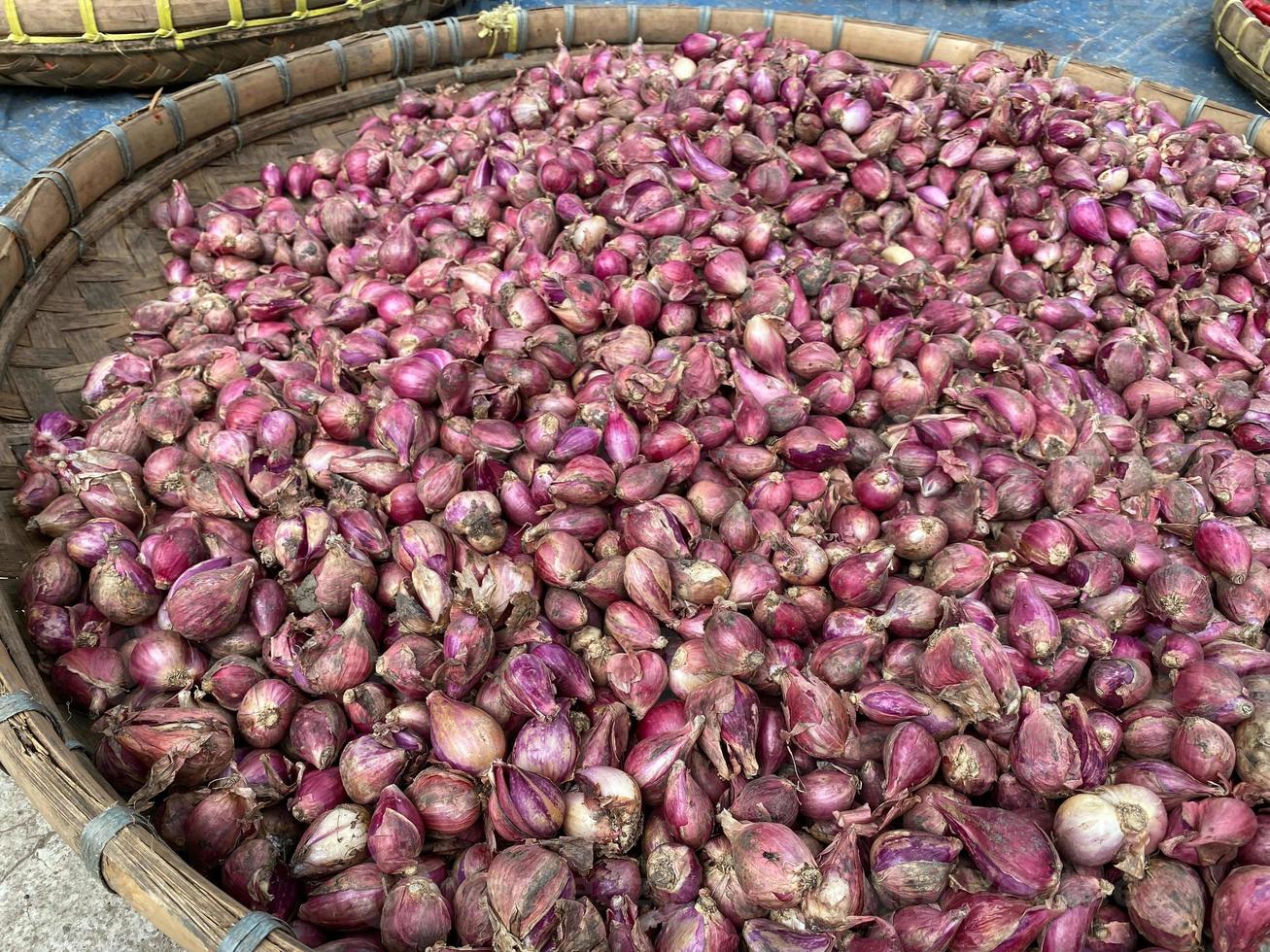 close up of red onion on round wooden tray in traditional market photo