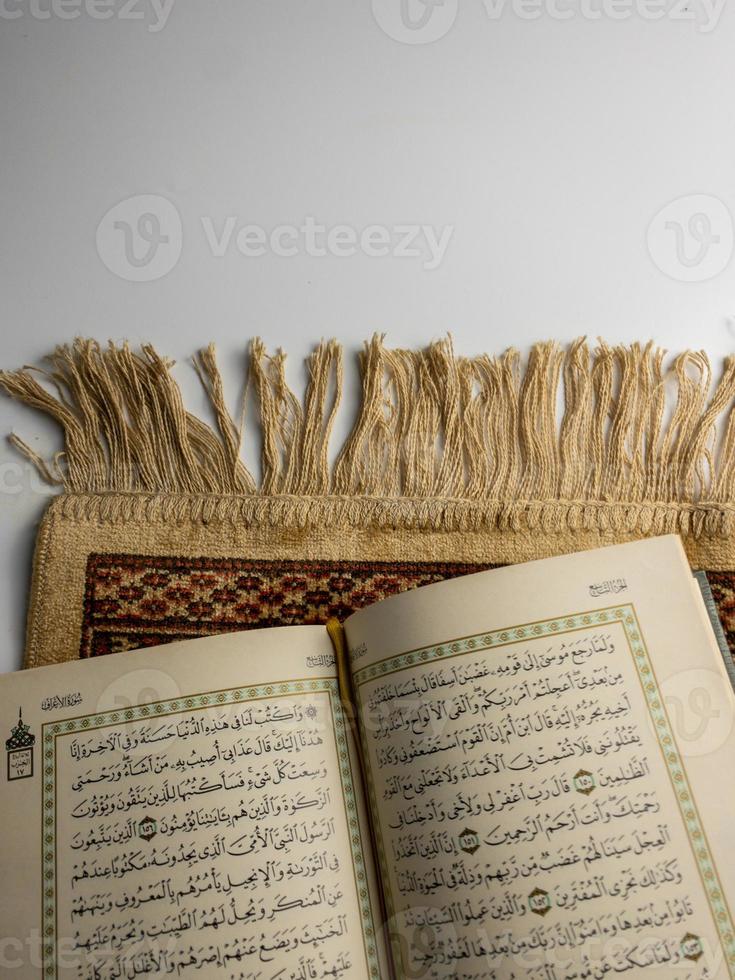 reading al quran and turning page of quran above sajadah praying mat isolated on white space. selected focus photo
