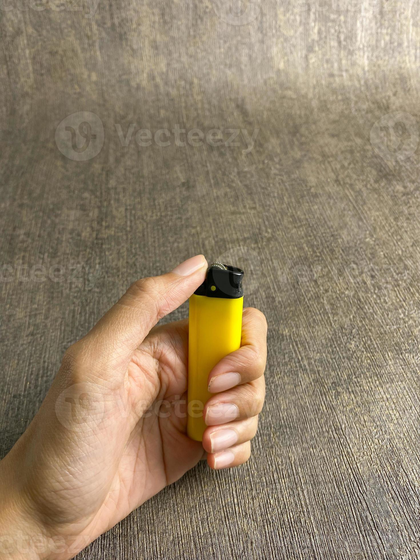 yellow lighter isolated on white background. hand tried to lit yellow