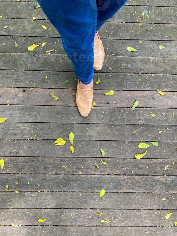 Women's legs in a simple brown shoes. top view of woman leg wearing shoes and skinny blue jeans. simple and street fashion. photo