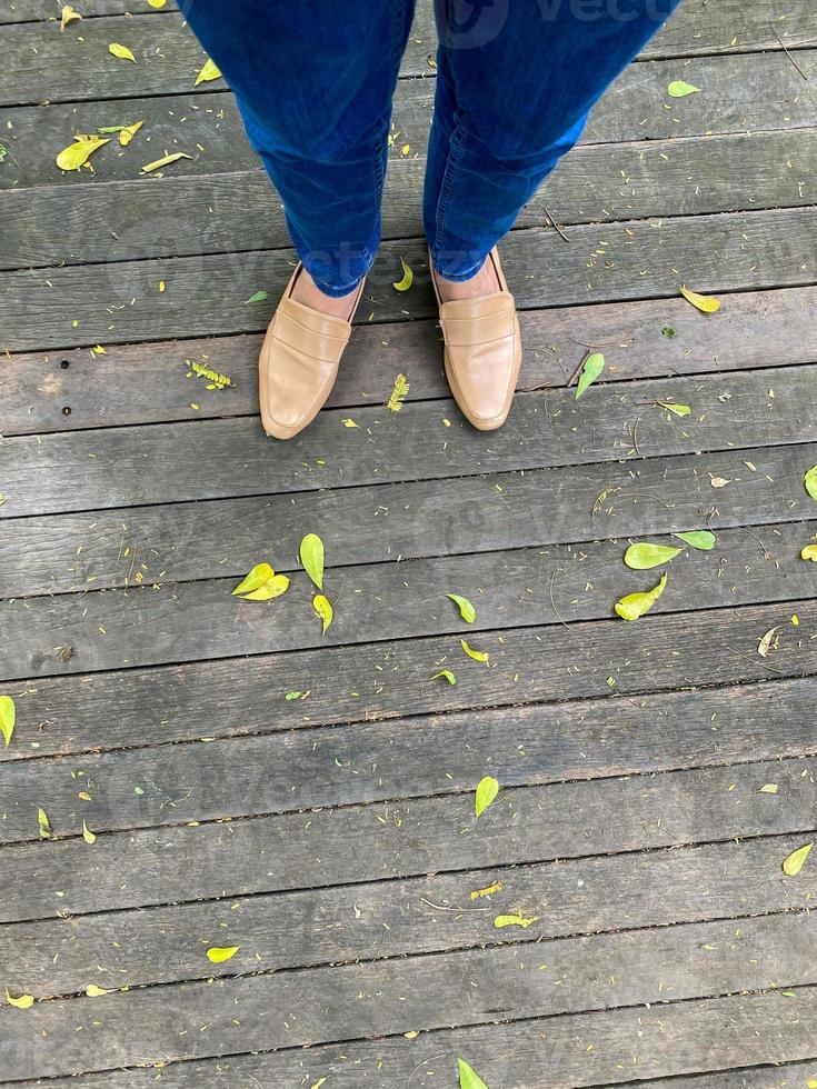 Women's legs in a simple brown shoes. top view of woman leg wearing shoes and skinny blue jeans. simple and street fashion. photo