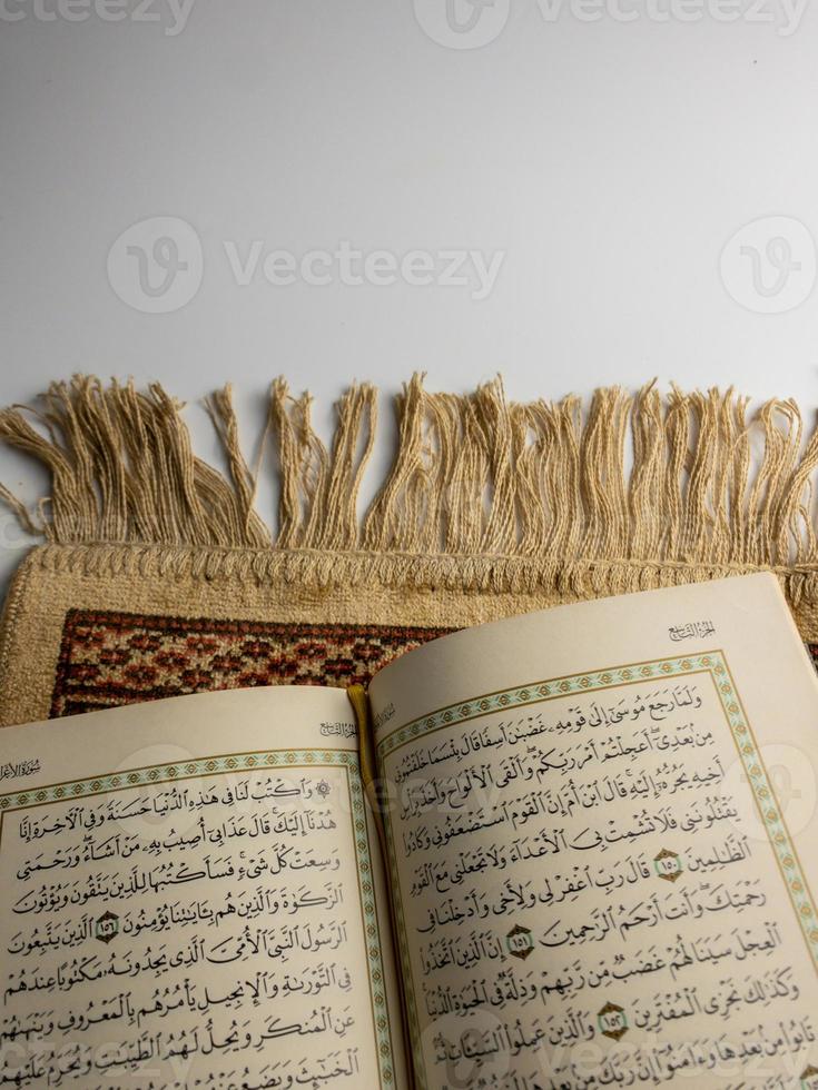 reading al quran and turning page of quran above sajadah praying mat isolated on white space. selected focus photo