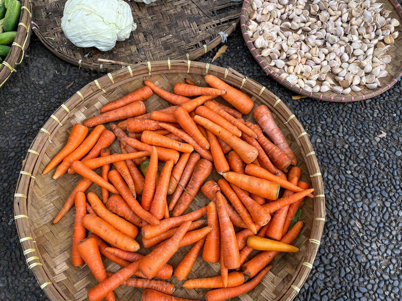 fresh, organic and imperfect carrots on round bamboo tray being sold at traditional market photo