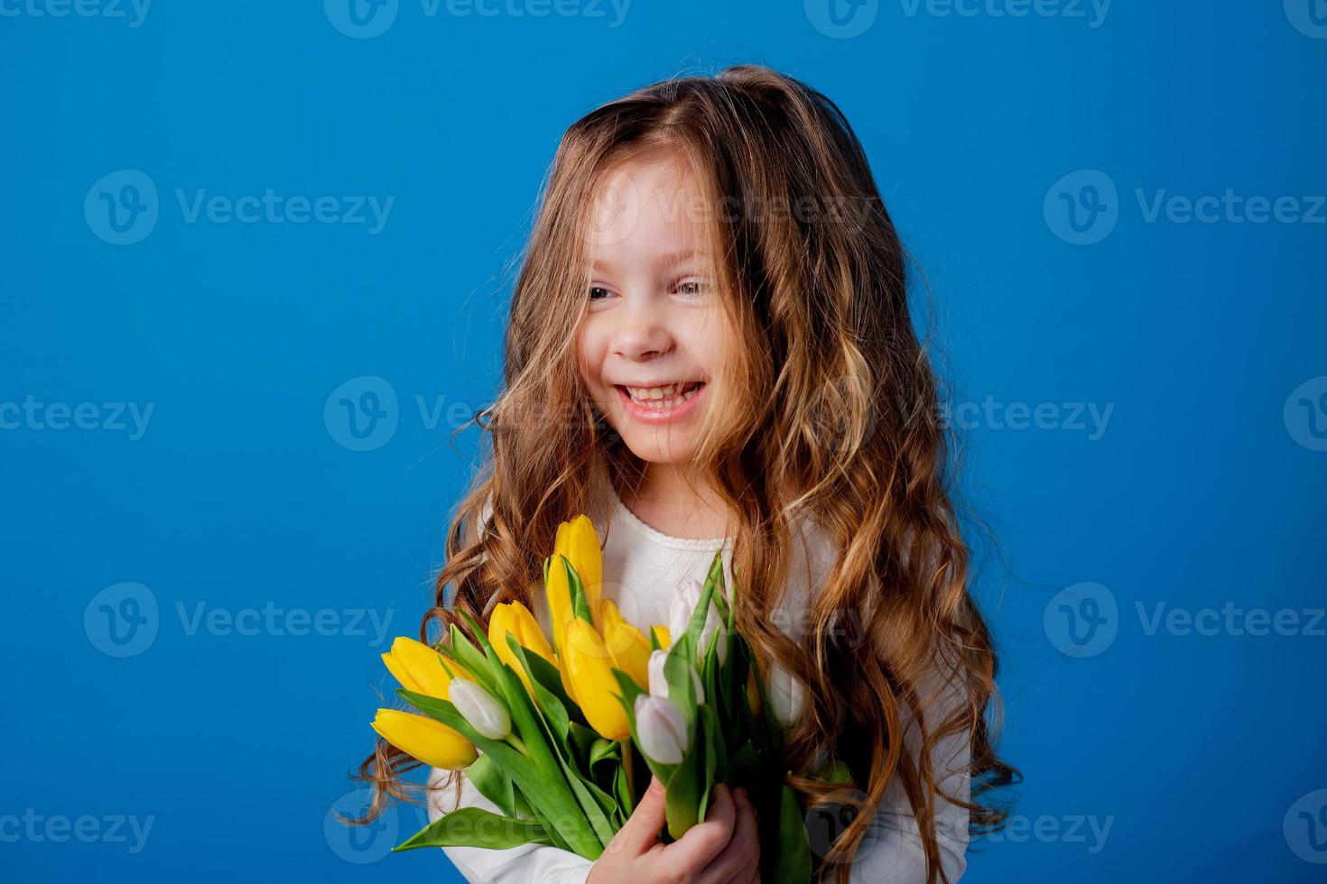 portrait of a charming smiling little girl with a bouquet of tulips in her hands. lifestyle. fresh flowers. International Women's Day. space for text. High quality photo
