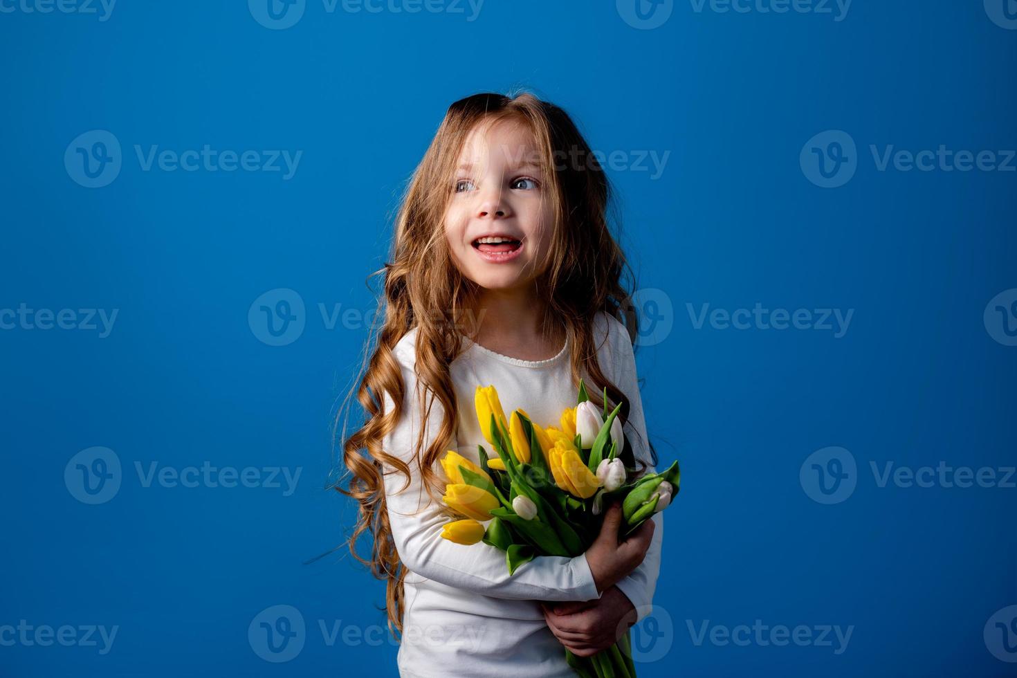 portrait of a charming smiling little girl with a bouquet of tulips in her hands. lifestyle. fresh flowers. International Women's Day. space for text. High quality photo