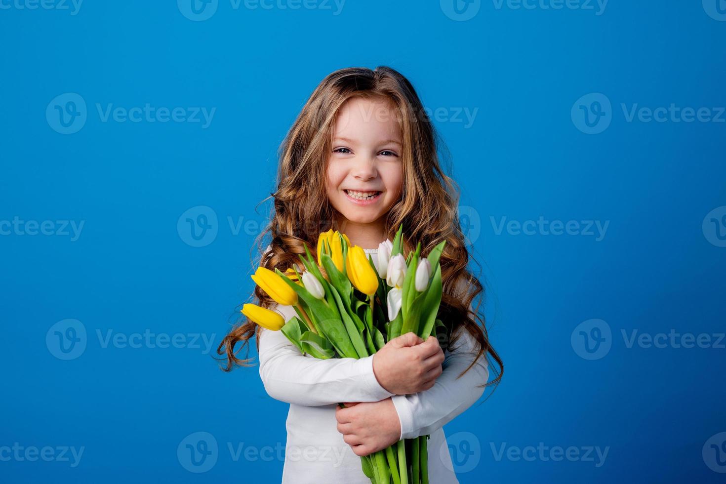 portrait of a charming smiling little girl with a bouquet of tulips in her hands. lifestyle. fresh flowers. International Women's Day. space for text. High quality photo