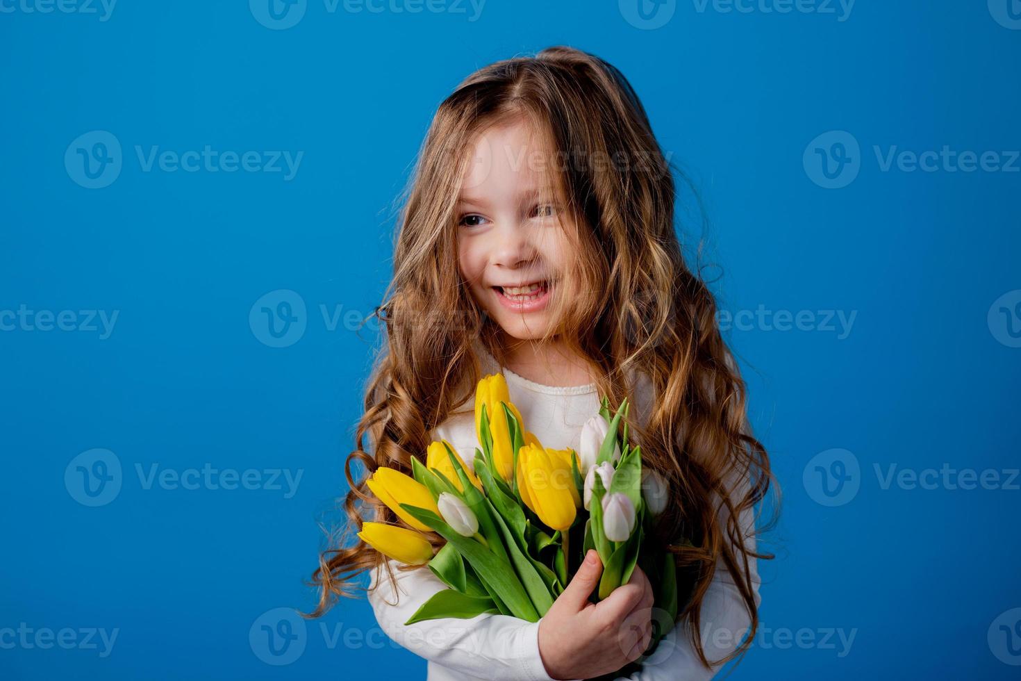 portrait of a charming smiling little girl with a bouquet of tulips in her hands. lifestyle. fresh flowers. International Women's Day. space for text. High quality photo