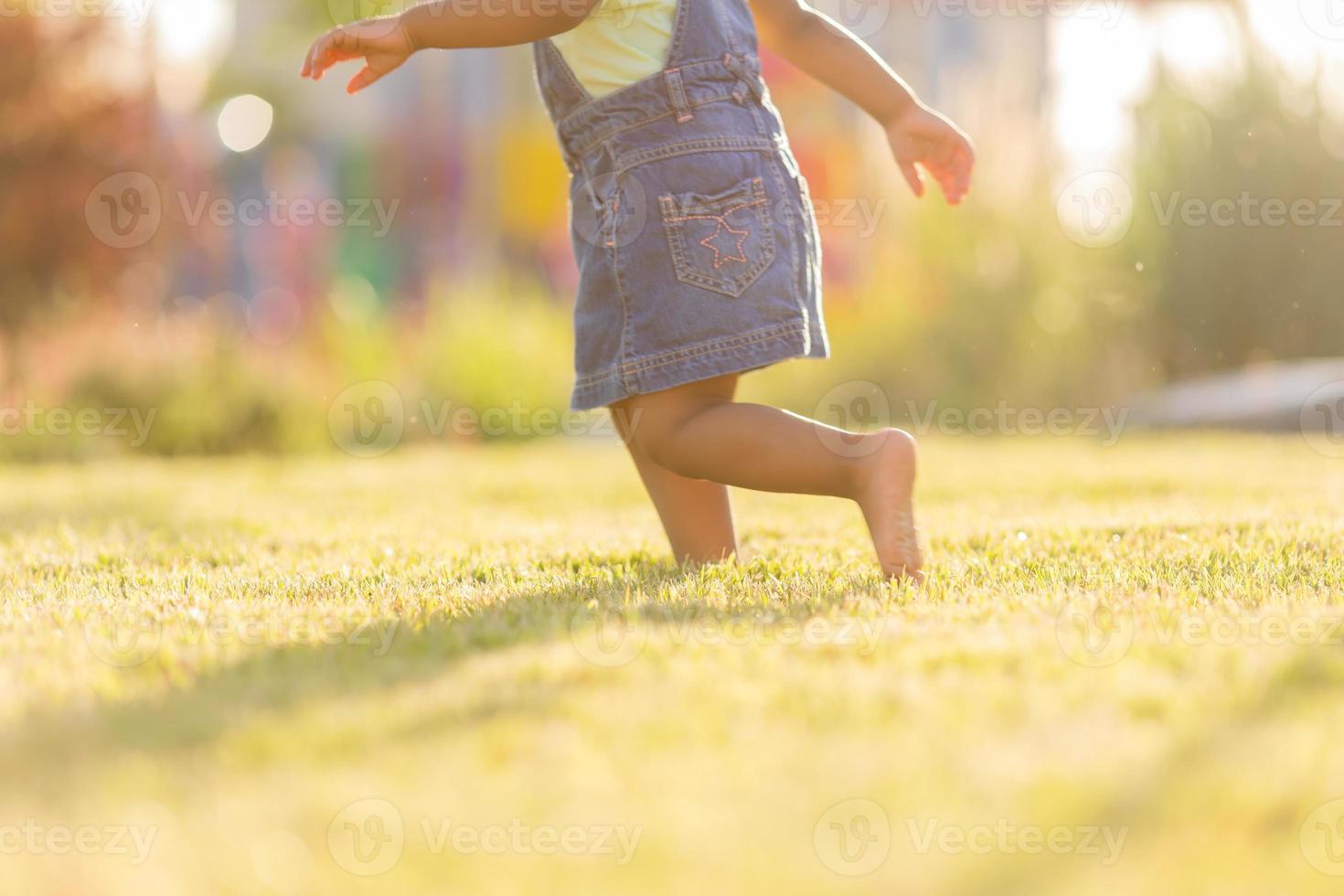 portrait little happy playful toddler swarthy girl in a denim sundress standing in the garden on a sunny day. walking in the fresh air. concept of a happy childhood. space for text. High quality photo