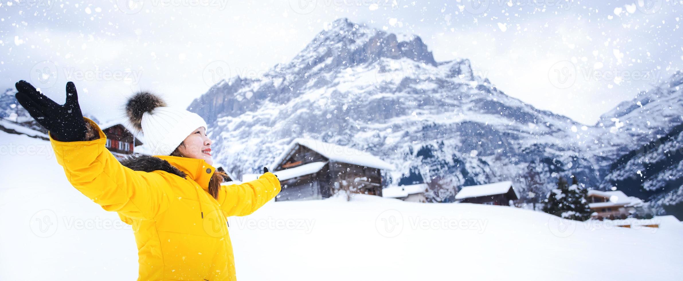 Grindelwald Switzerland top of Europe, Asian woman wearing yellow coat.She is feel Very happy on vacation in the mountains Background.travel trip  Snowy winter on Mount Grindelwald in Switzerland, photo