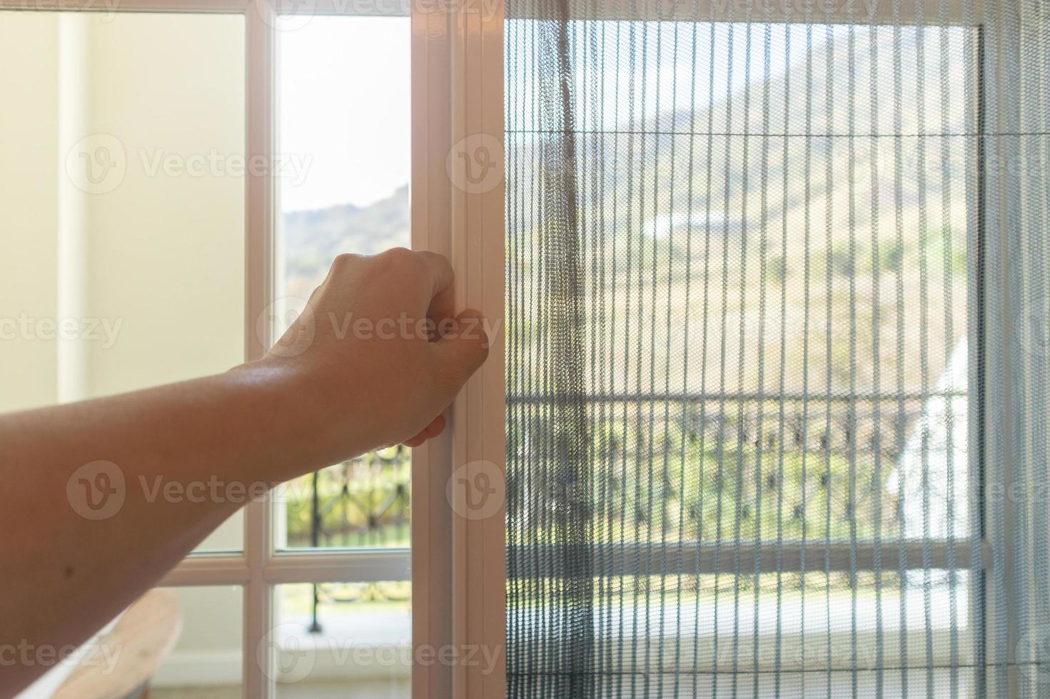 Hand hold pleated mosquito net wire screen handle on house window photo