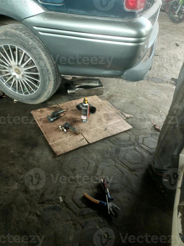 el coche es siendo reparado con mecánico equipo debajo foto