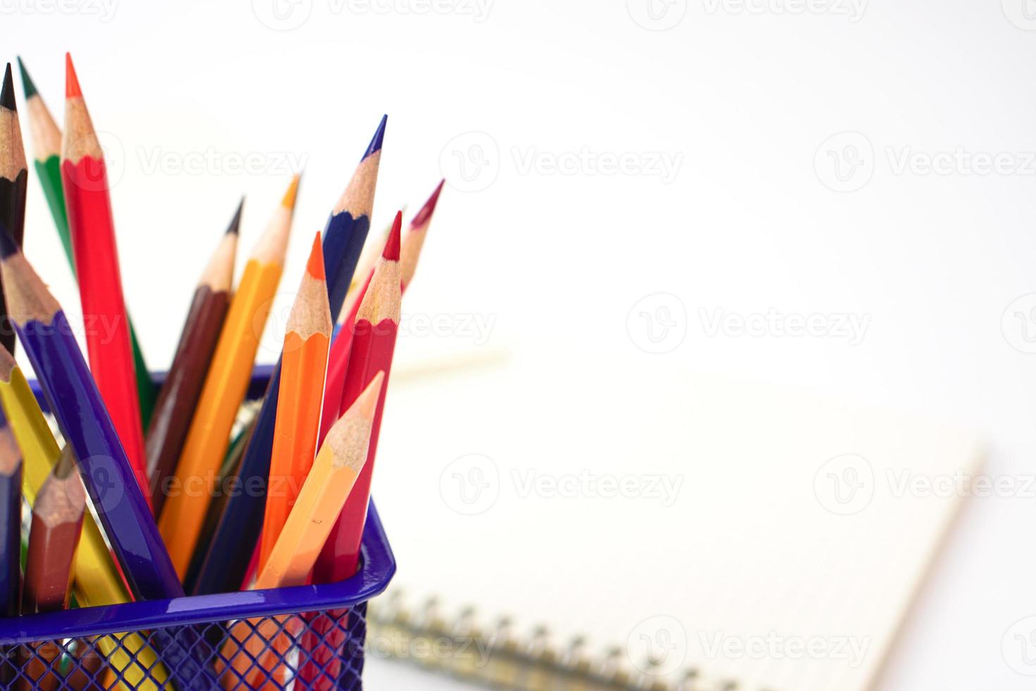 Crayon or colored pencils in box and the book placed in the blurred background. photo