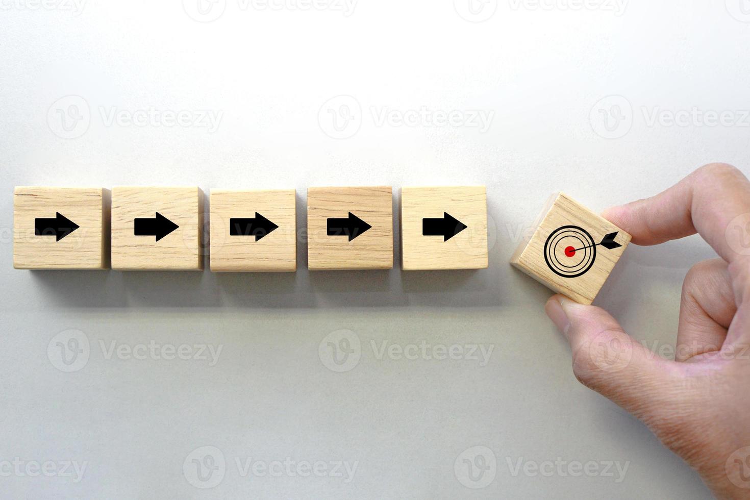 Hand holding a wooden block cube with target icon symbol. Business strategy and target of business. photo