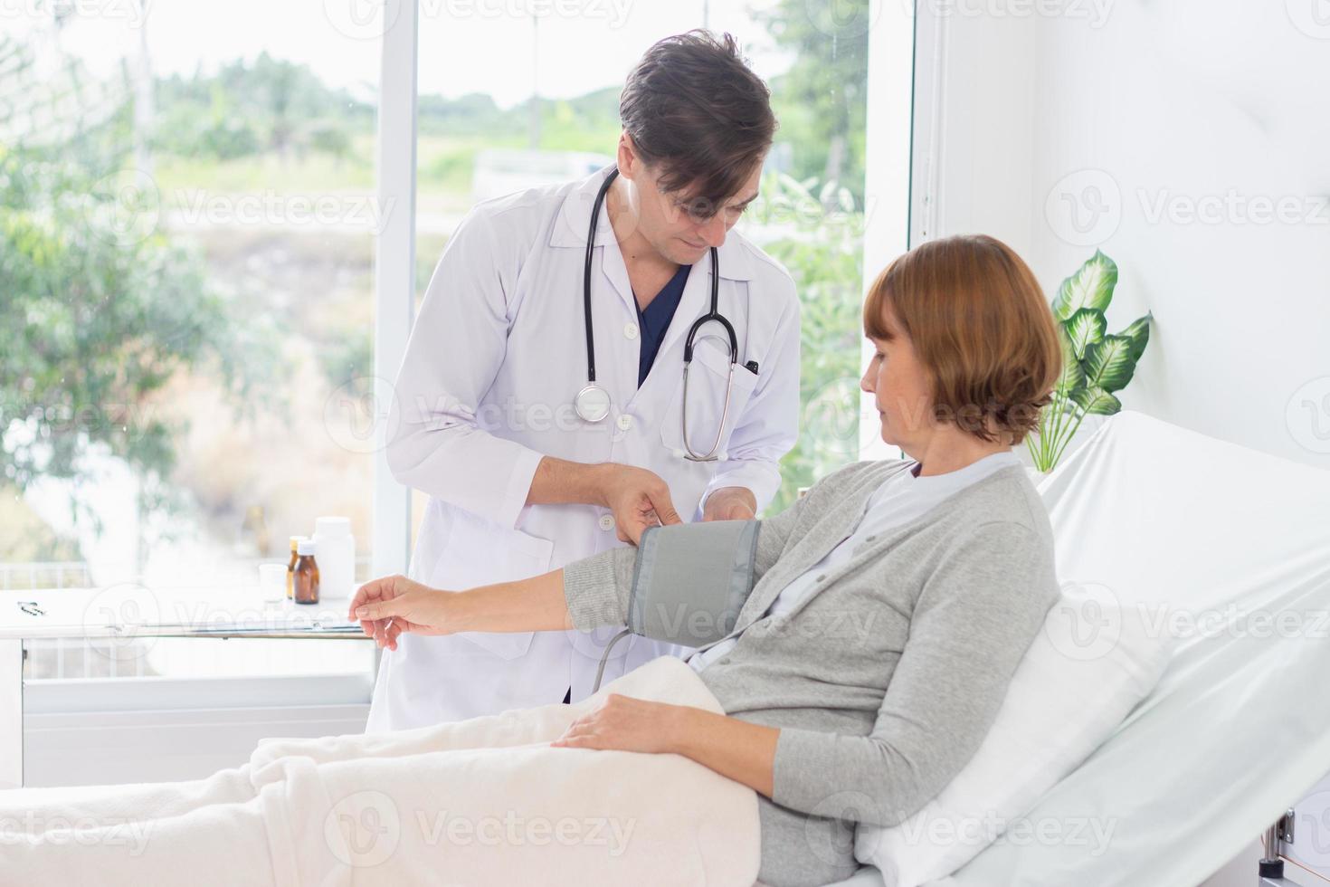 Caucasian male doctor measuring blood pressure of female patient in hospital. photo