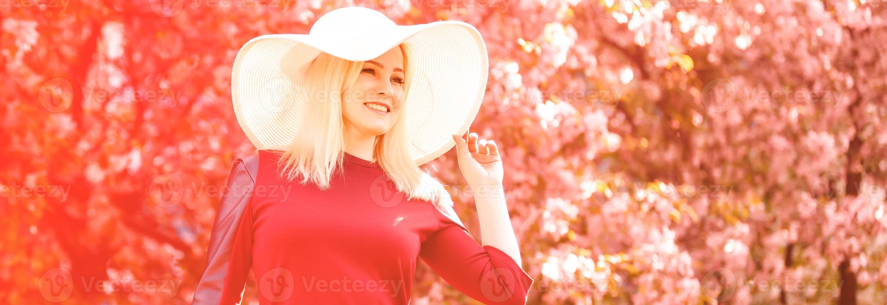 hermosa primavera niña en fragante rosado flores en verano florecer parque. mujer en un floreciente jardín . moda, productos cosméticos perfumes . Rizado rubia pelo foto