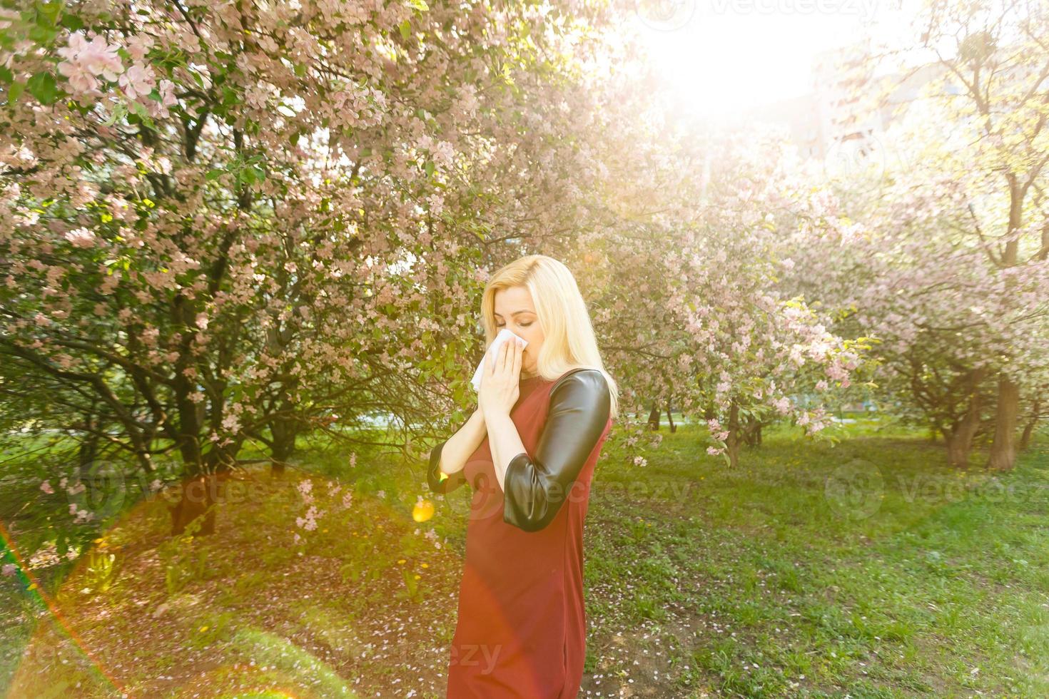 Woman with allergy symptoms blowing nose photo