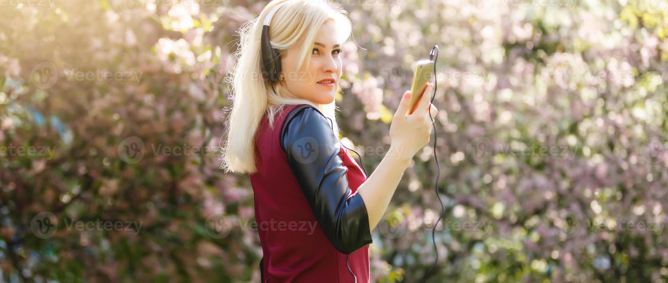 Beautiful young woman in a headphones listening music in the park. Instagram photo