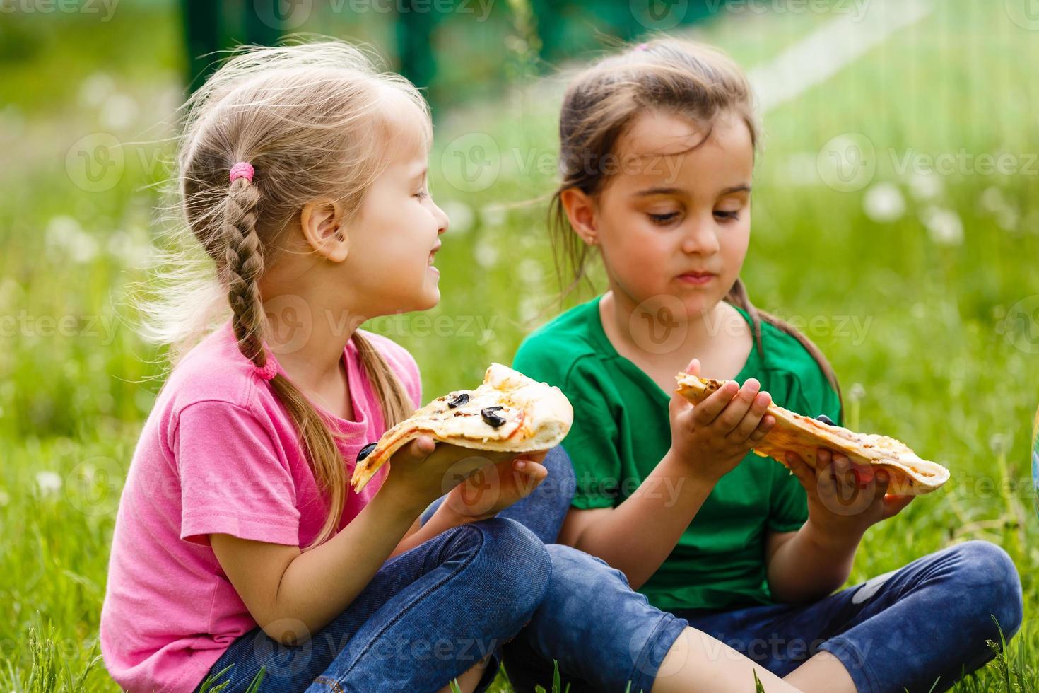 Two girls sitting and eating pizza photo