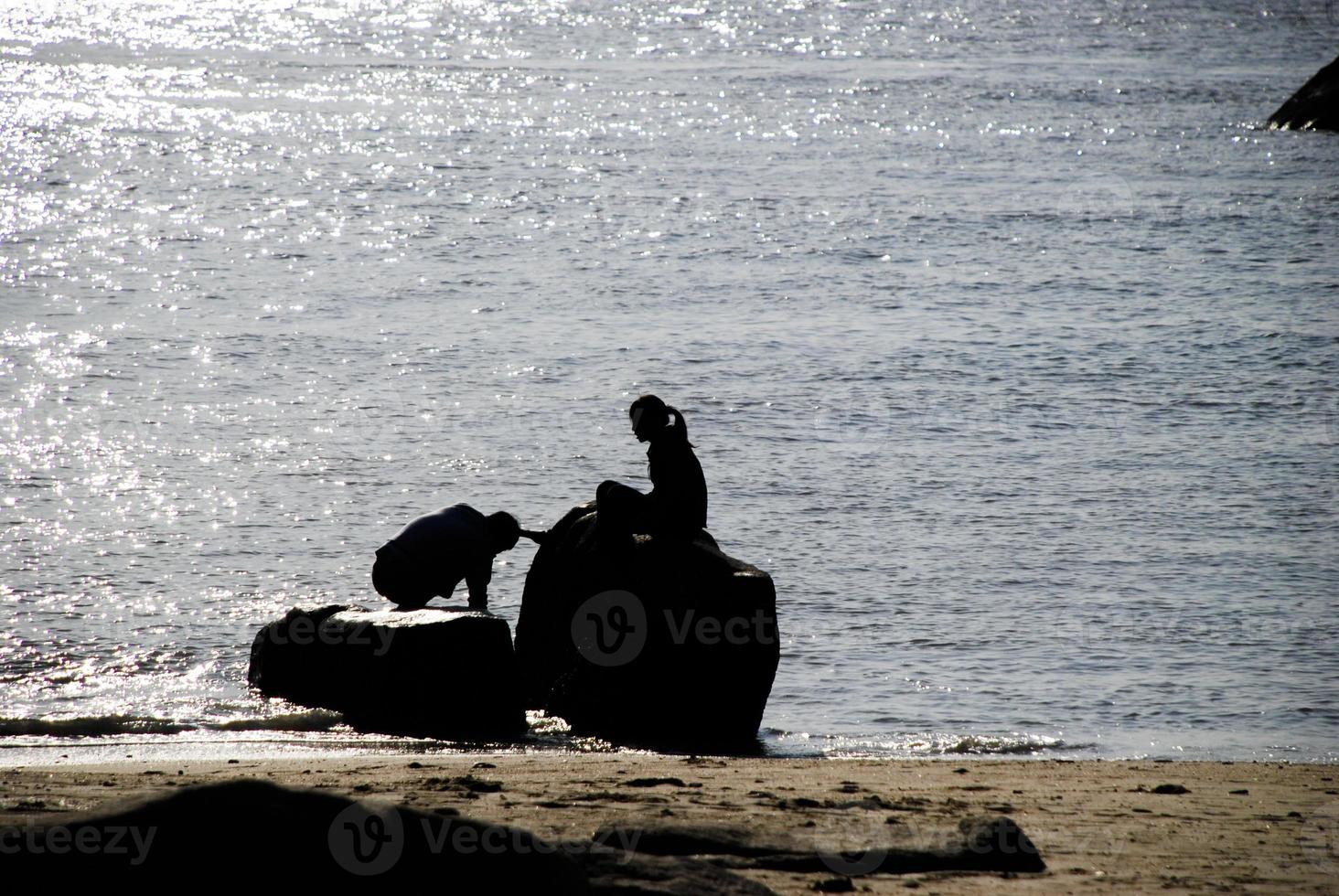 amantes sentado en rocas en el playa foto