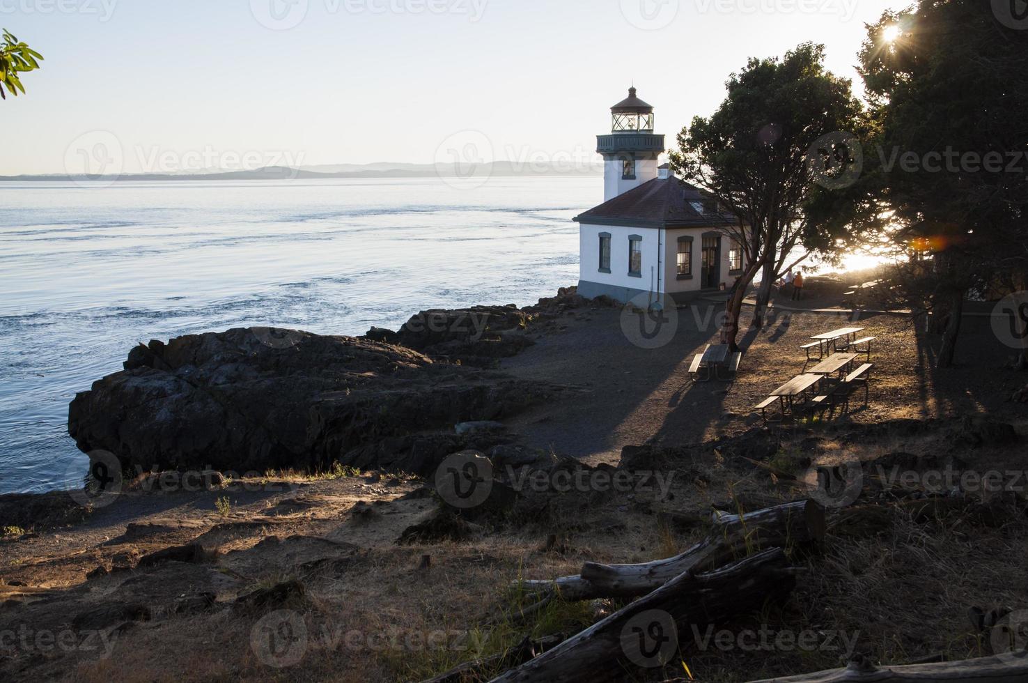 White lighthouse on the coast at sunset photo