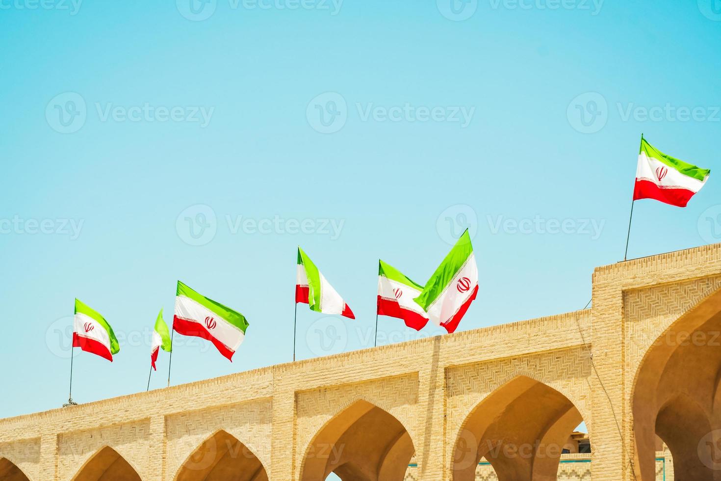 Many iranian flags wave in wind on rooftop of building photo