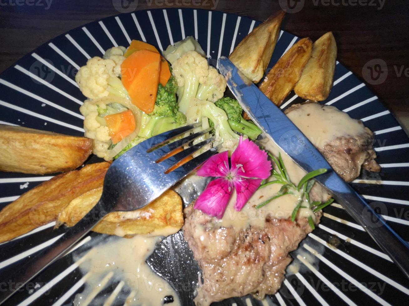 Juicy beef steak with salad and potato wedges along with pepper corn sauce photo