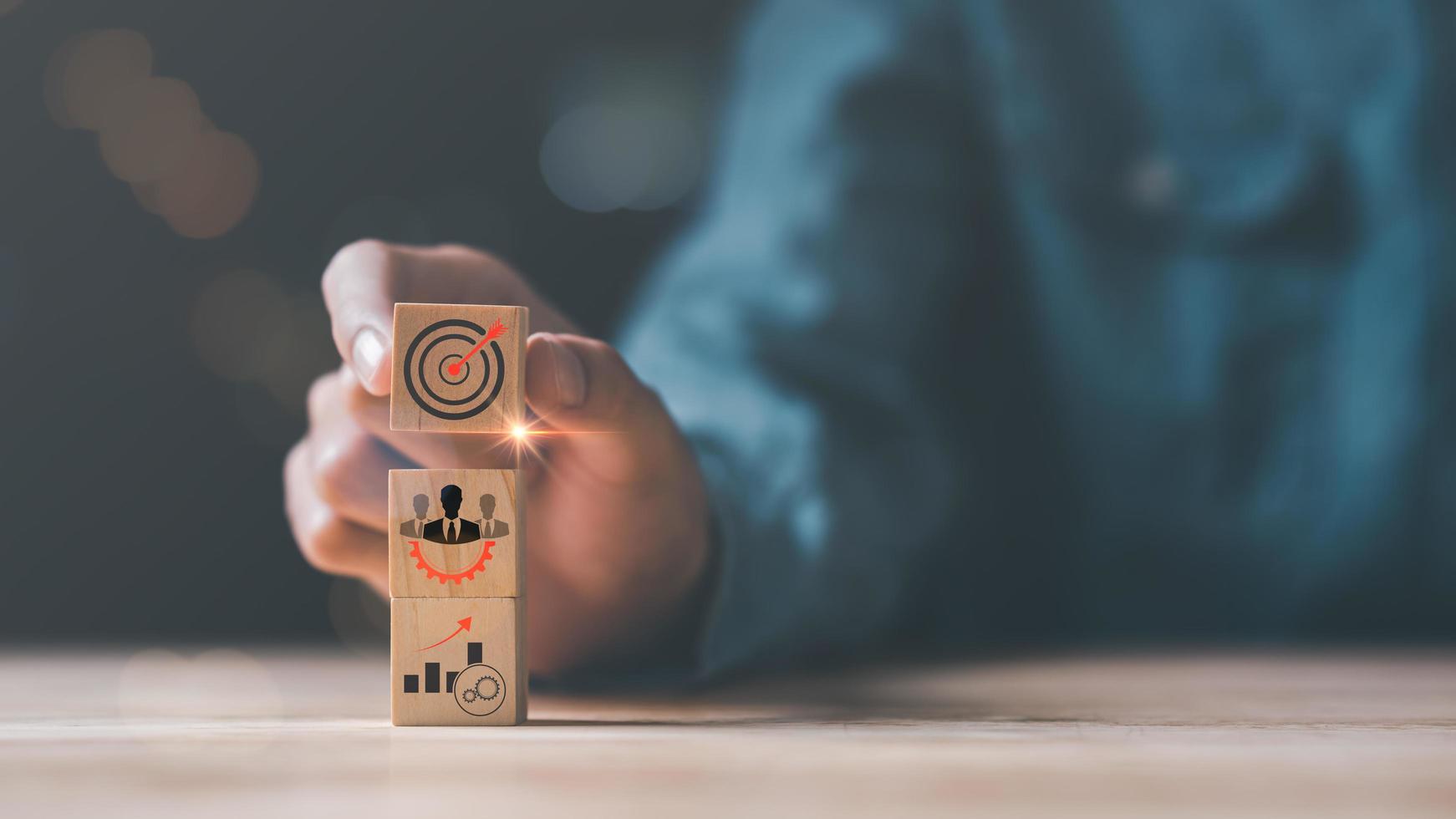 Wooden block in businessman hand and arrow icon hitting center of dartboard target,Setting business goals and focused concepts, Organizational growth and objectives, marketing strategy planning photo