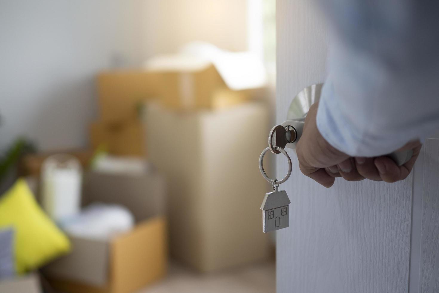 mudanza, reubicación. la llave se insertó en la puerta de la nueva casa, dentro de la habitación había una caja de cartón que contenía objetos personales y muebles. mudarse al departamento o condominio foto