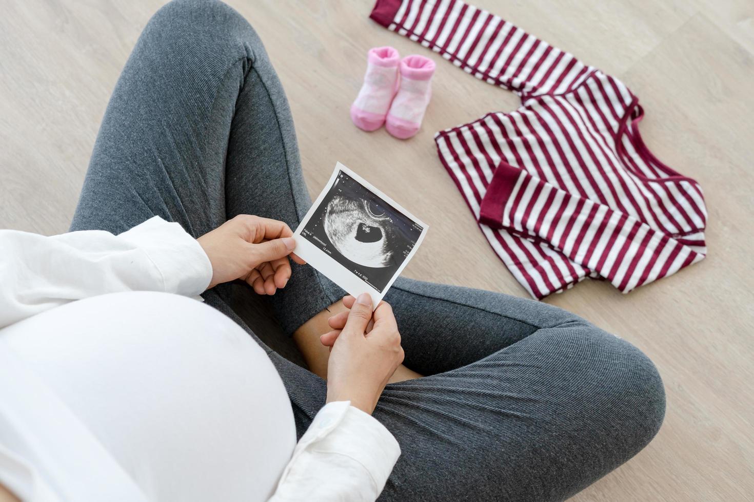 una mujer embarazada está revisando y preparándose por teléfono móvil para el recién nacido. la cesárea es una manera para que las mujeres embarazadas sepan una fecha de parto. concepto de preparación para la madre. foto