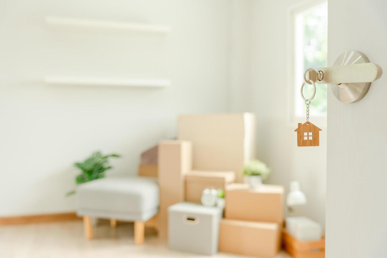 Moving house, relocation. The key was inserted into the door of the new house, inside the room was a cardboard box containing personal belongings and furniture. move in the apartment or condominium photo