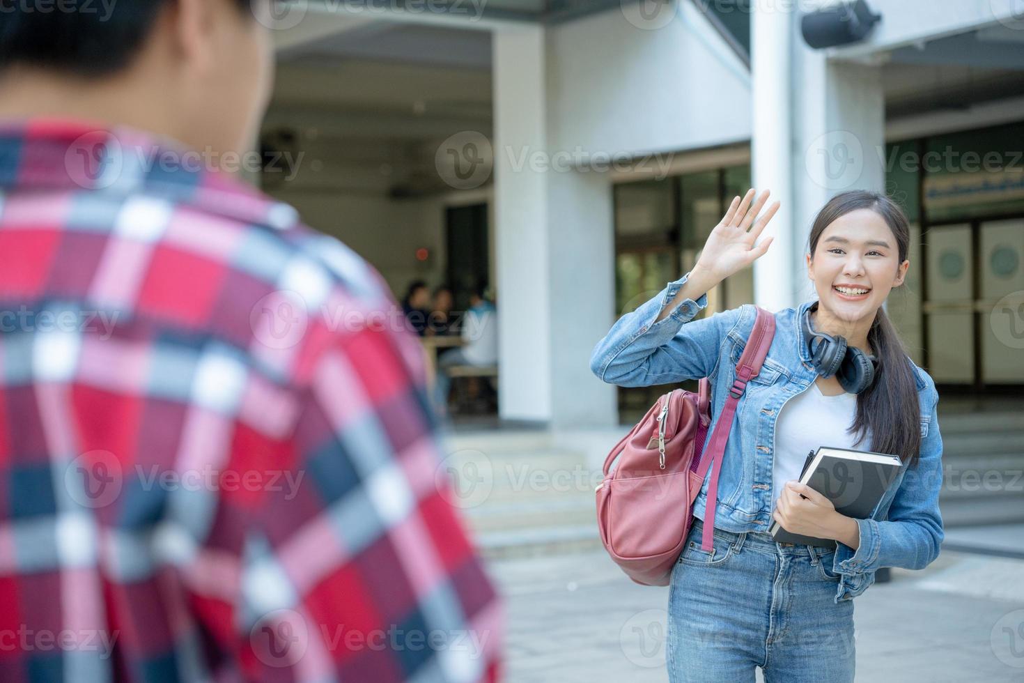 Beautiful student woman with backpack and books outdoor is greeting friends. Smile girl happy carrying a lot of book in college campus. Portrait female on international Asia University. Education photo