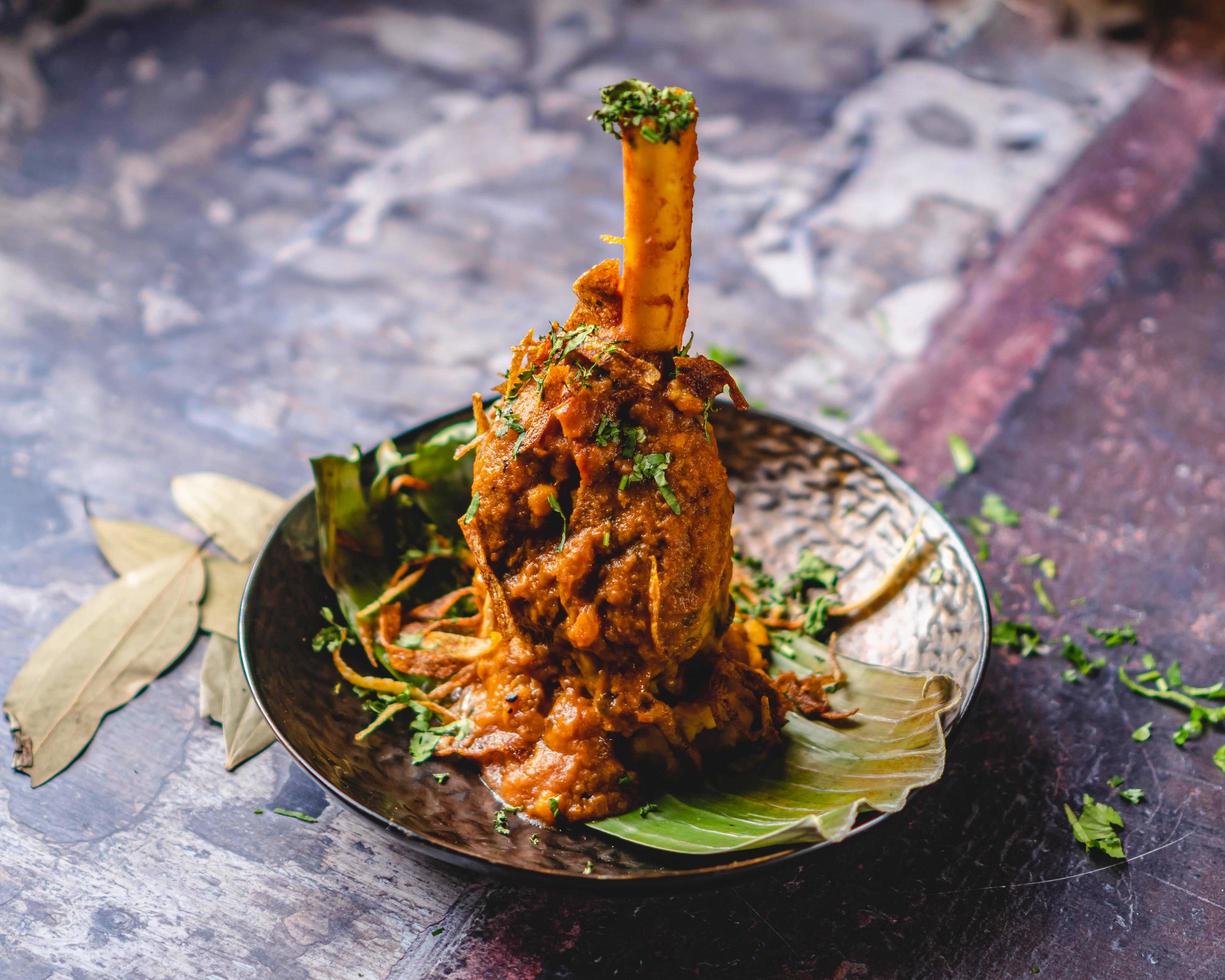 Nalli gosht is served with bright leaves, banana leaves, and coriander. cult of the lamb, bone scepter. photo