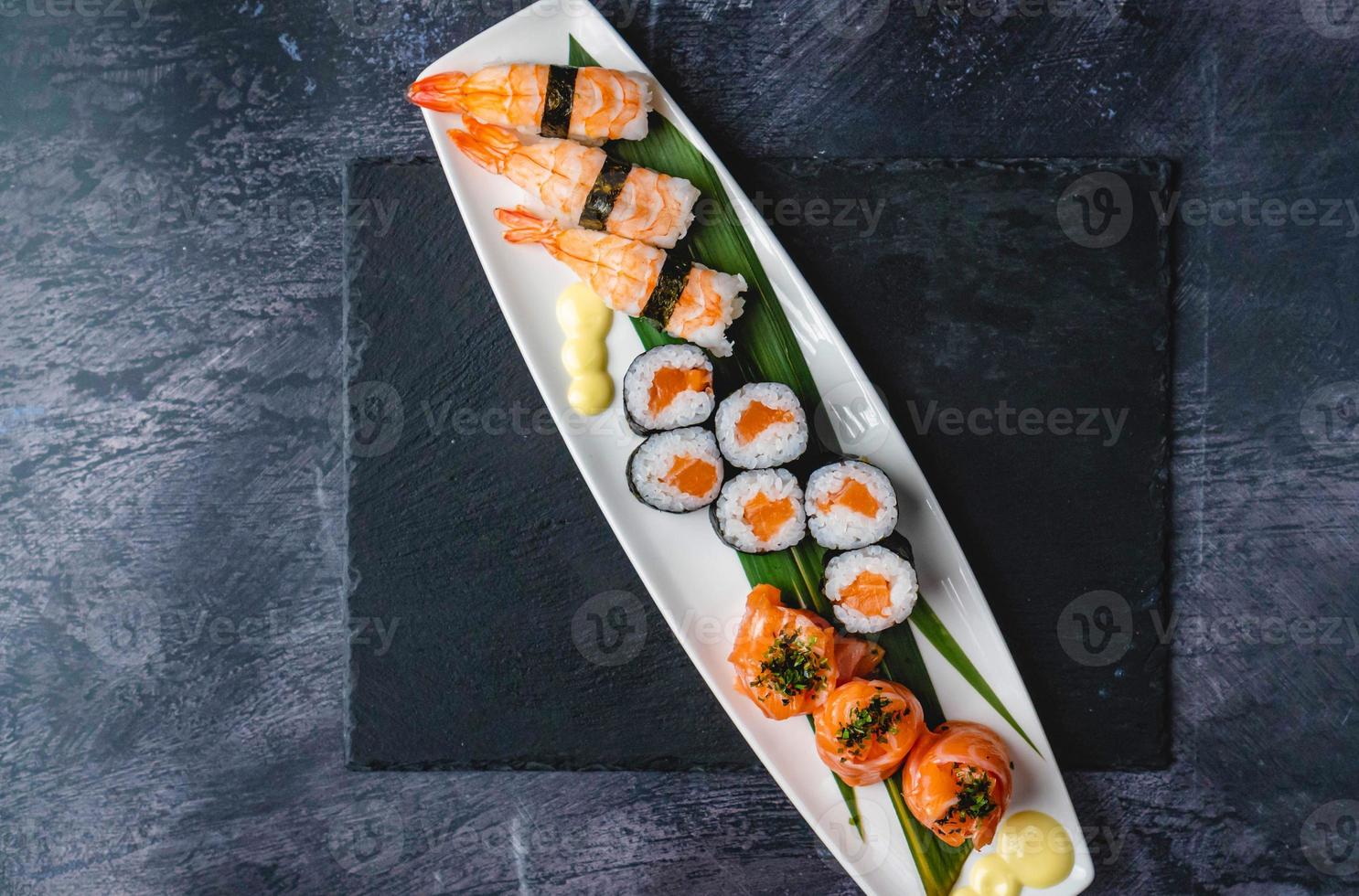 Salmon jhow sushi, Nigiri sushi, and Salmon hosomaki sushi on a black table with a black mate under the plate. photo