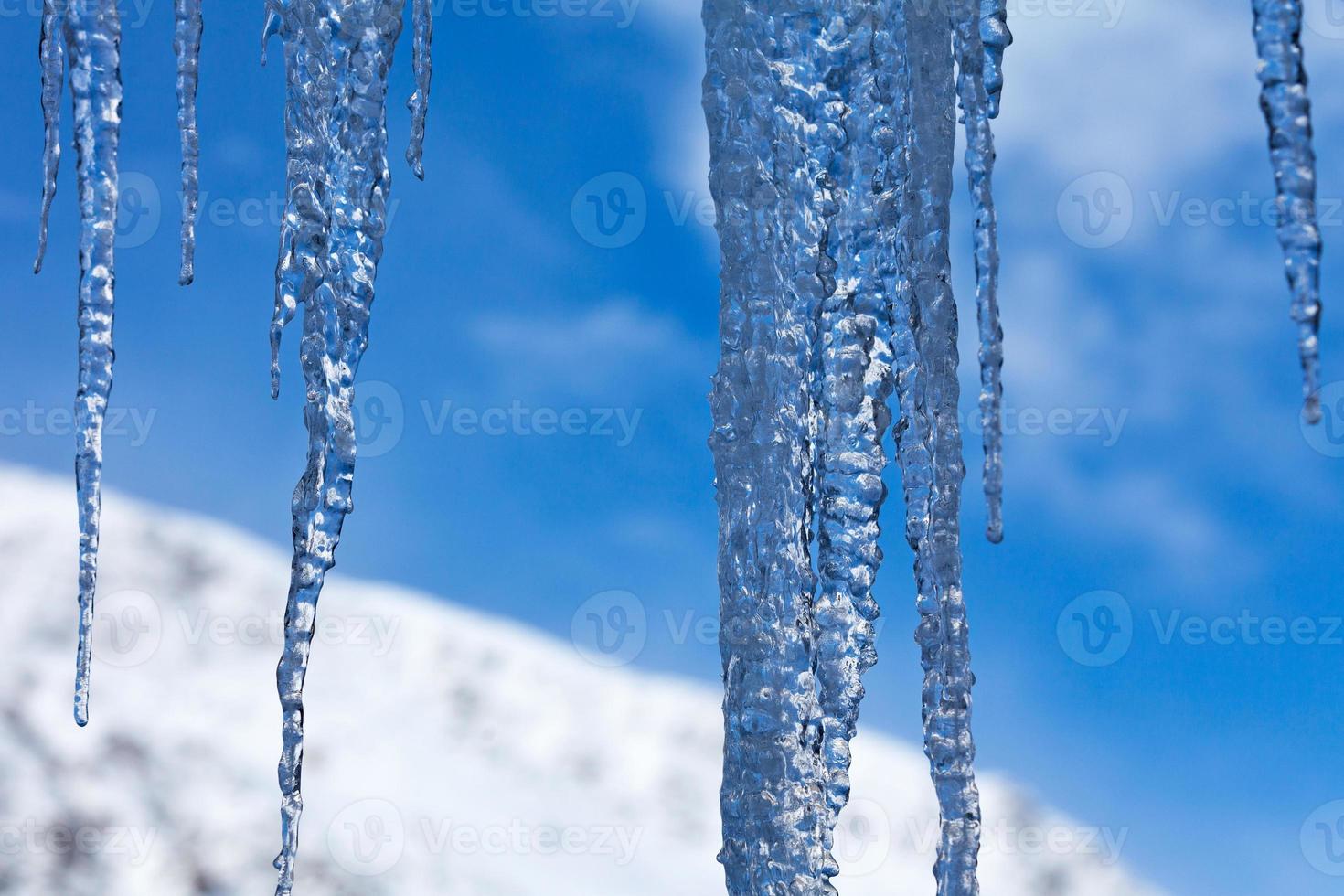 Ice stalactites in front of a snow-capped mountain photo