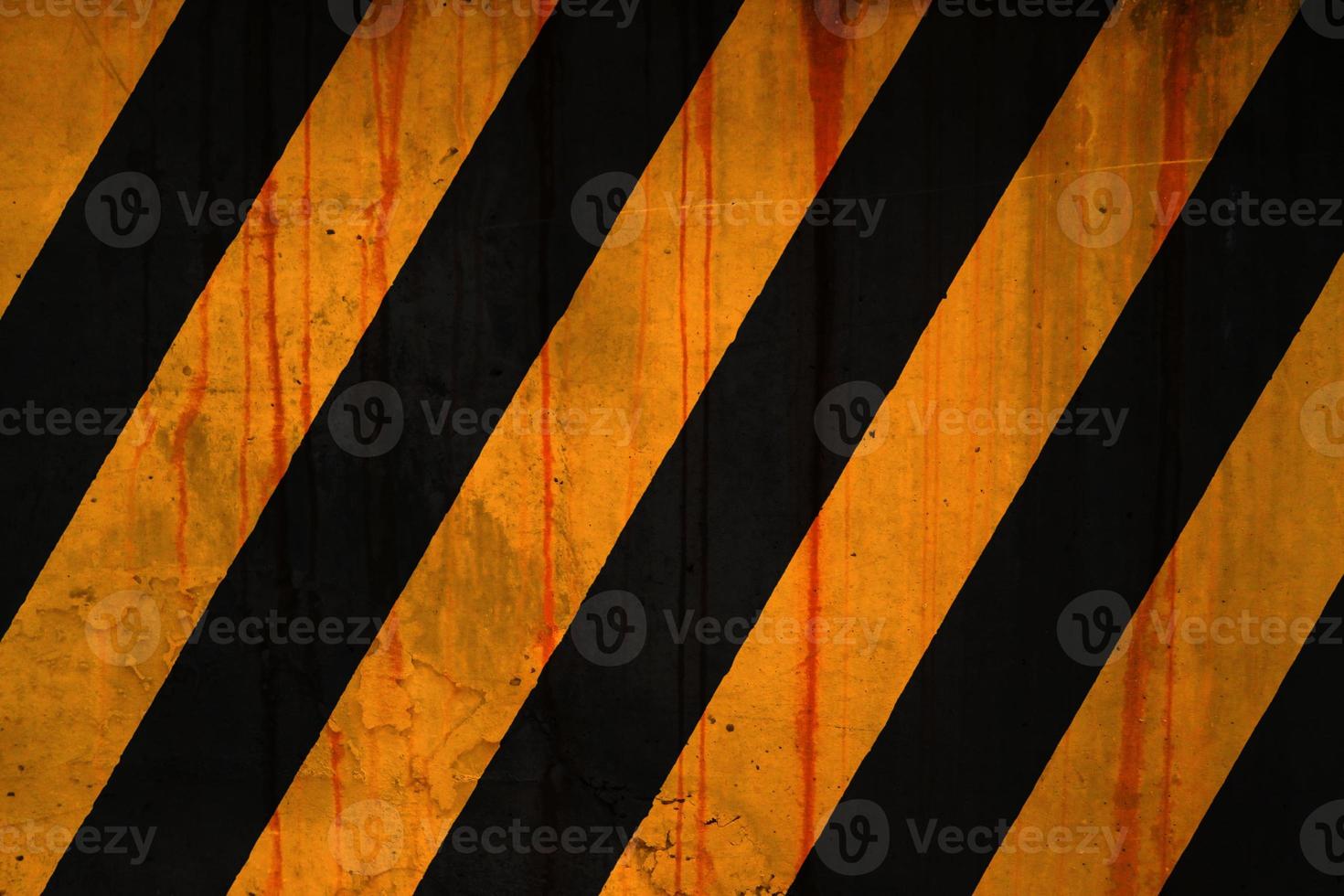 Concrete wall covered with rust stains and paint in yellow and black stripe photo