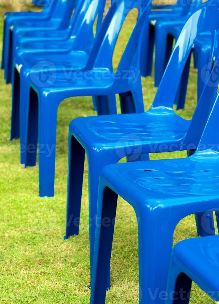 Row of blue plastic chair on green lawn photo