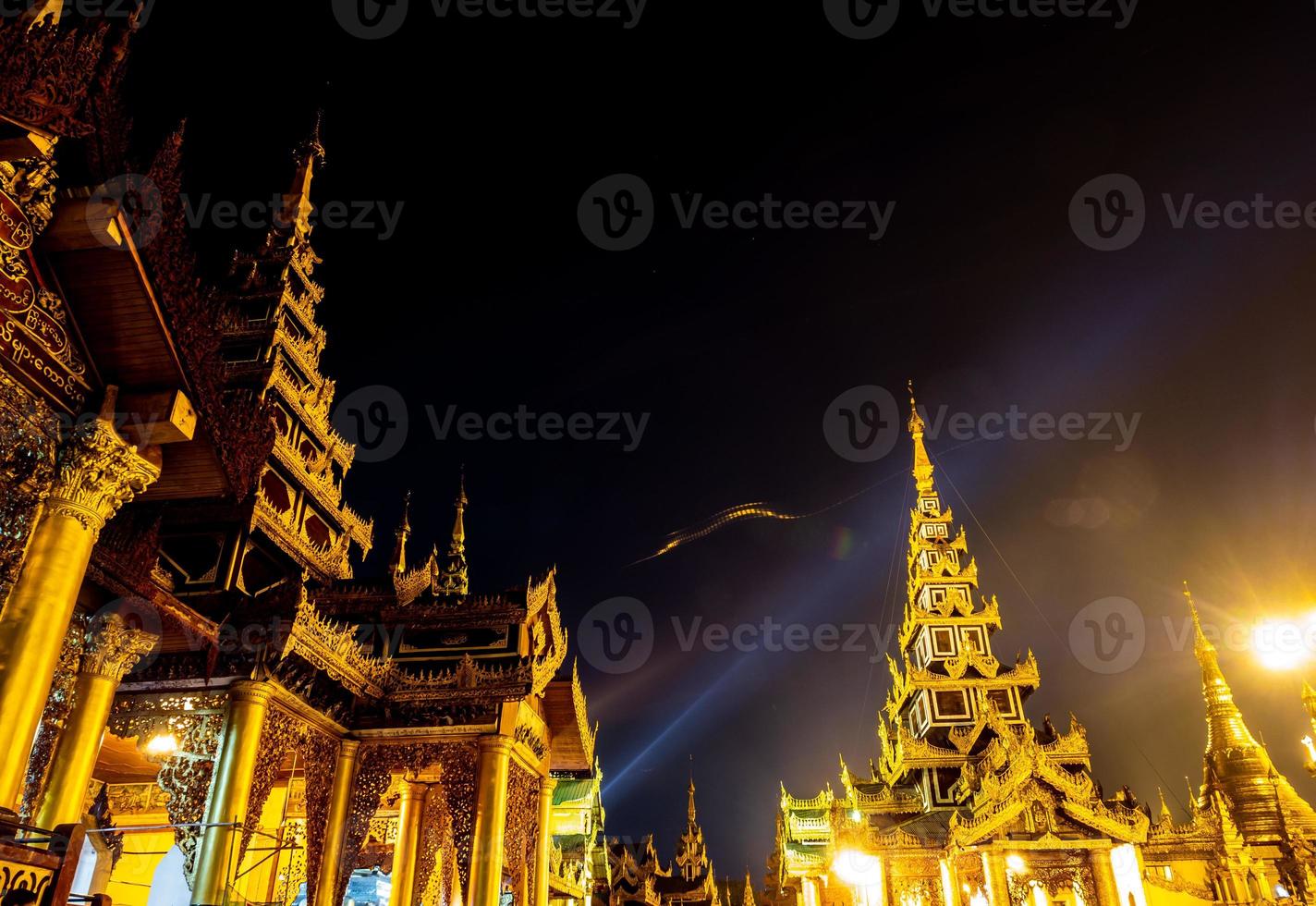 The golden pagodas and mondops are illuminated in the light of the night photo
