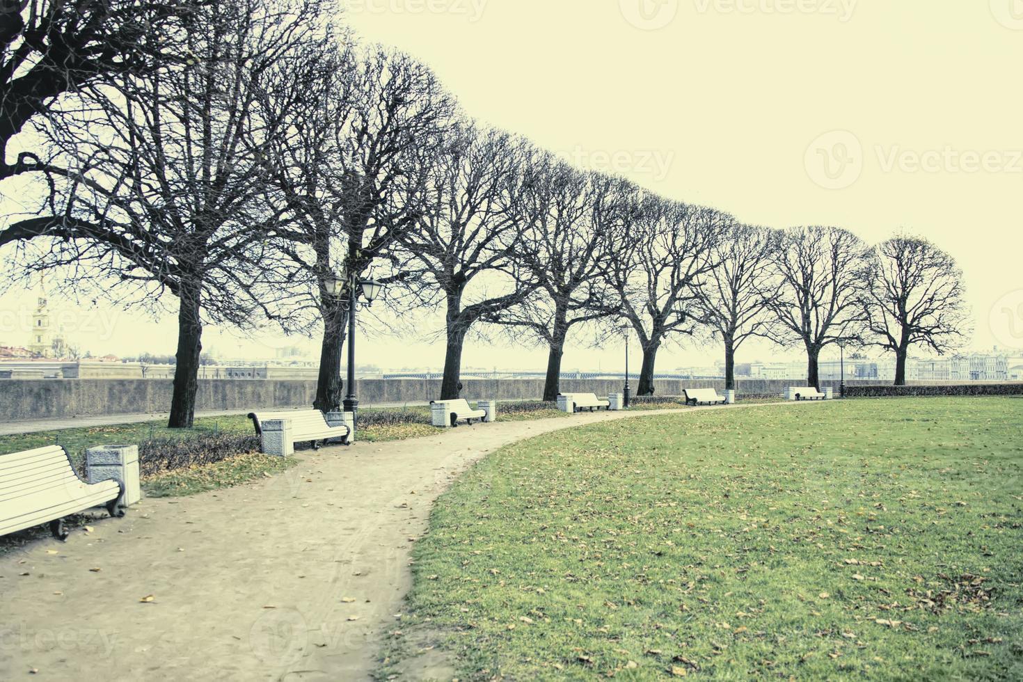 Vintage dull city park landscape with footpath and benches in faded colors. photo