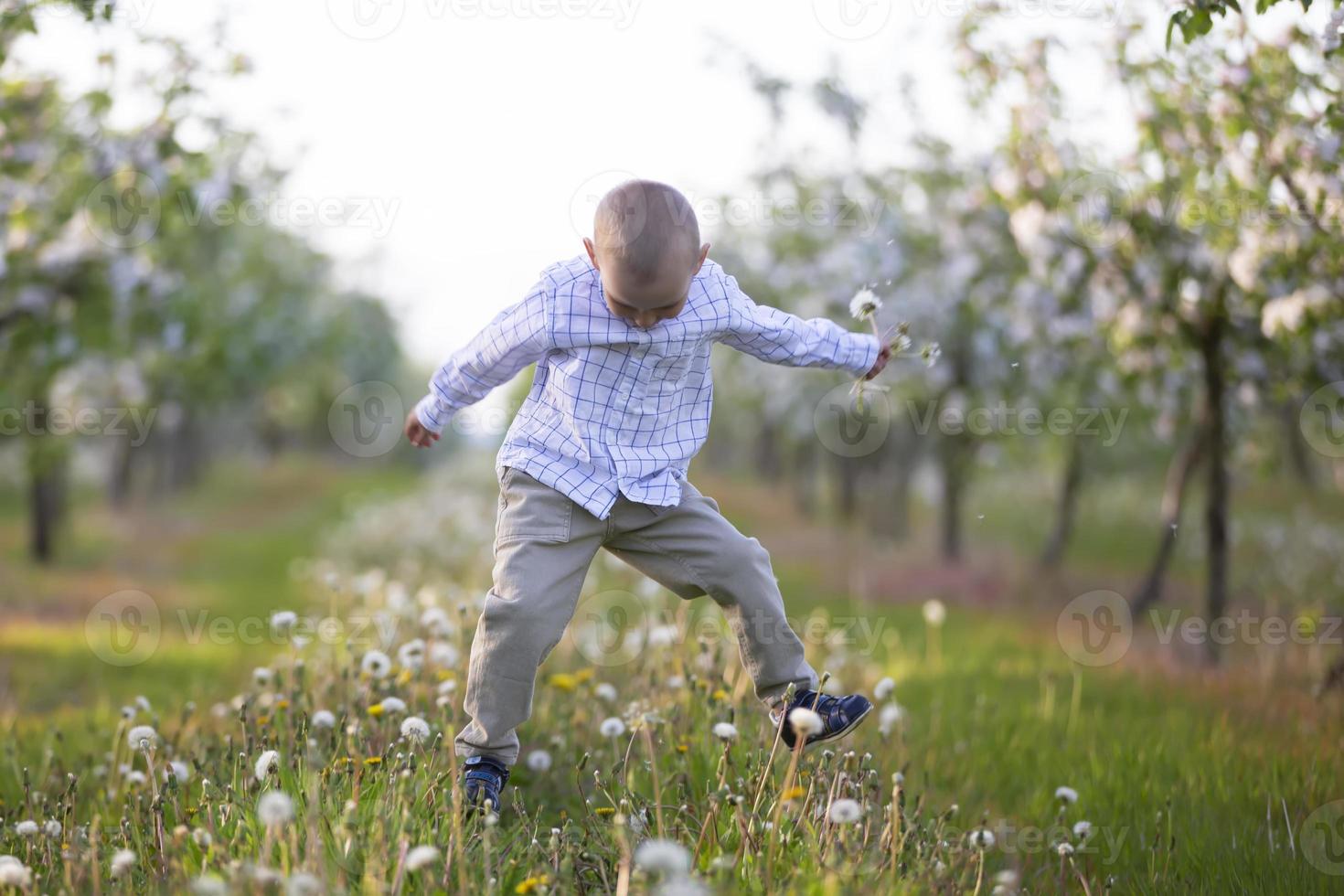 A happy child in a blooming spring garden plays, jumps, he is in a good mood. photo