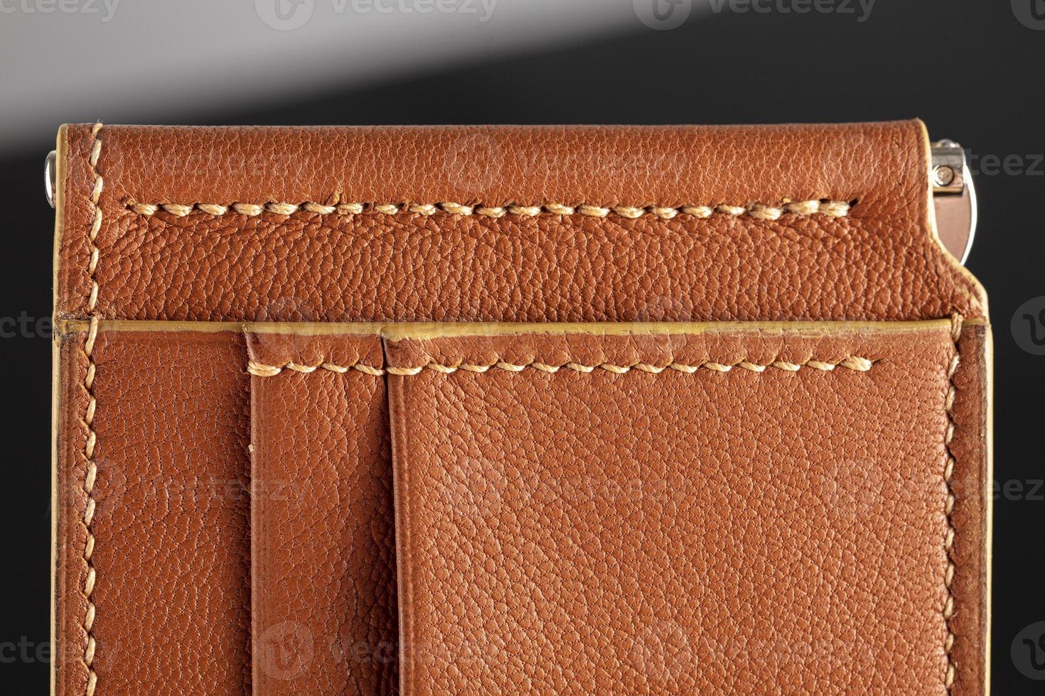 Part of a brown leather wallet or case with stitching. photo