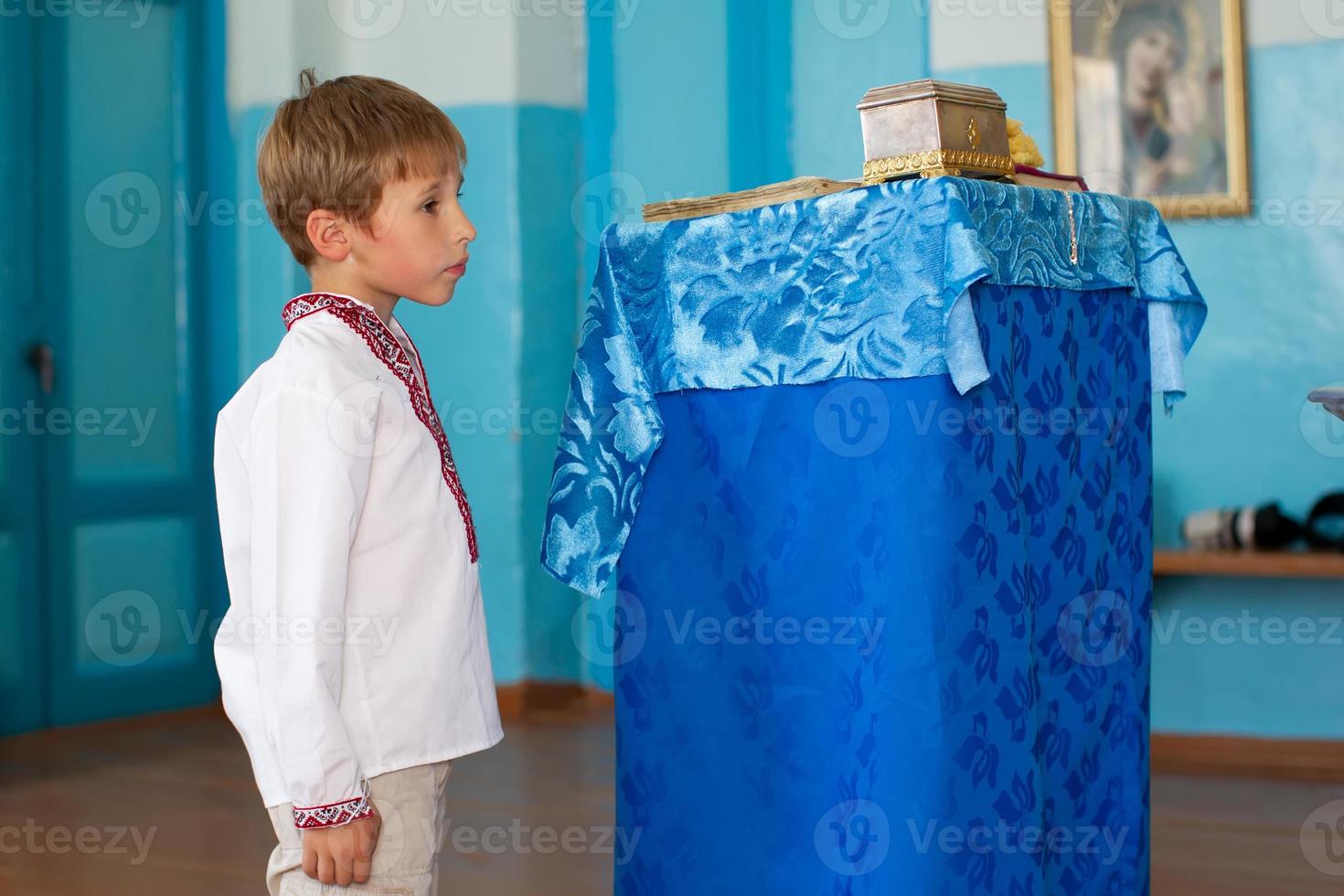 A little Belarusian or Ukrainian boy in an embroidered shirt in a church. photo