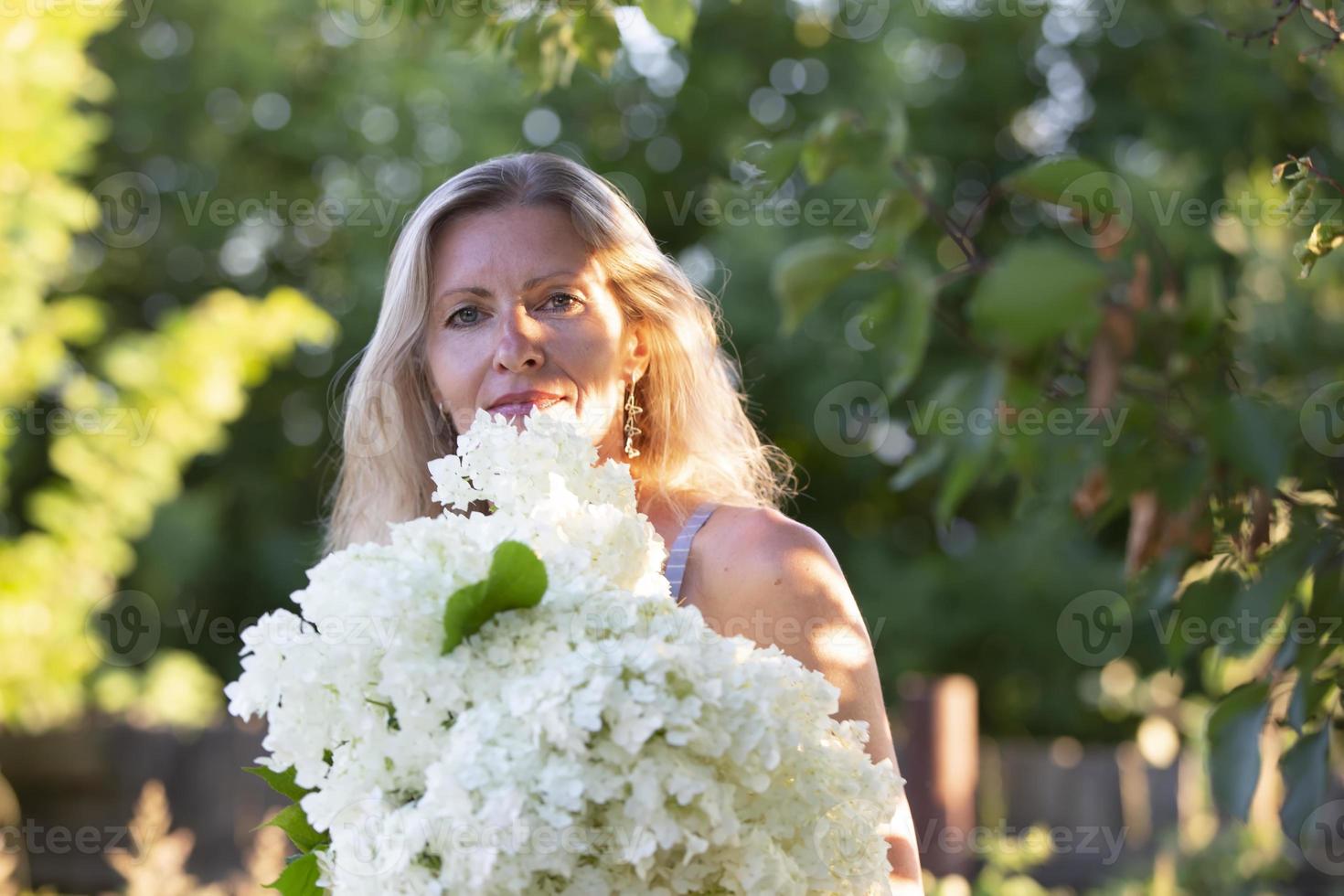 hermosa mayor mujer posando en el jardín con un ramo de flores de flores foto