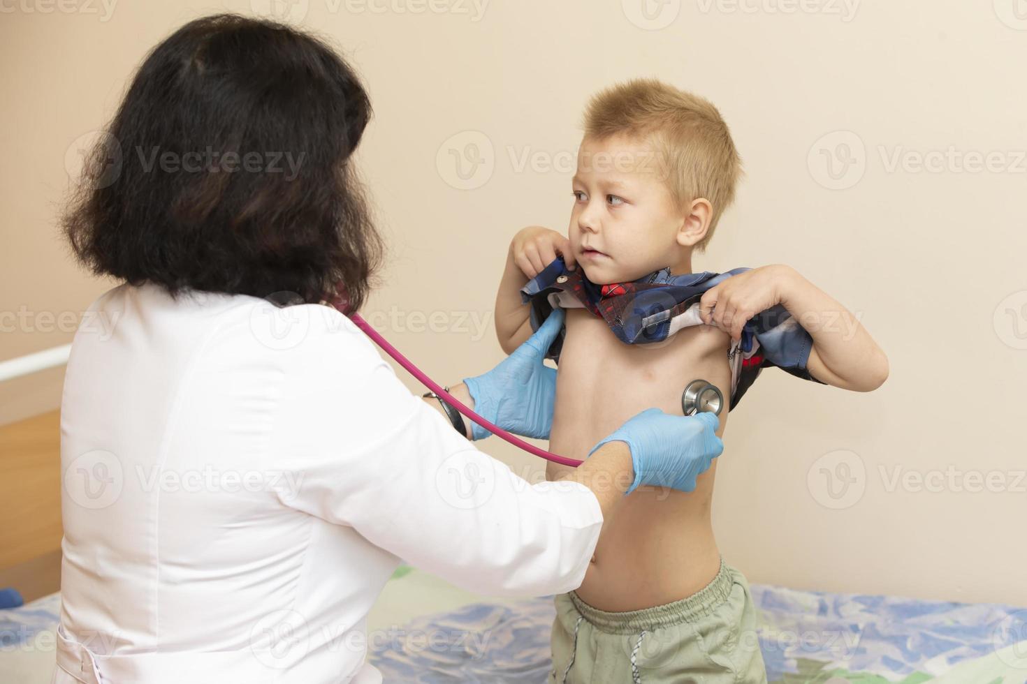 The doctor uses a stethoscope on the boy's stomach to check his health. photo