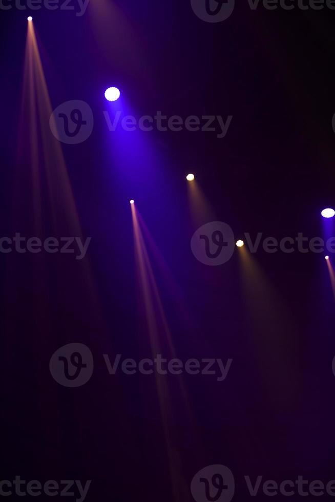 Purple beams of light from stage spotlights on a dark background. photo