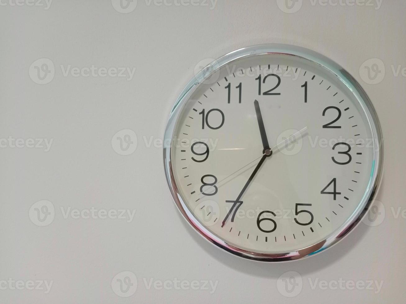 clock hanging on the white wall with copy space photo