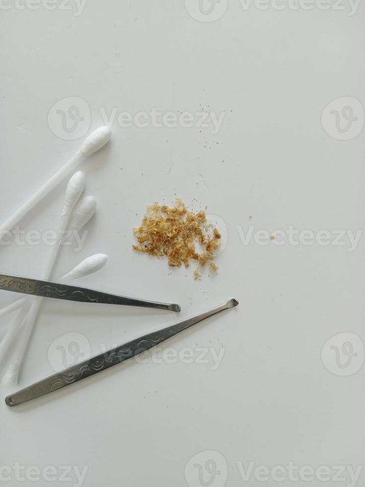 Earwax and two ear pick tools and cotton swabs On the light blue table top photo