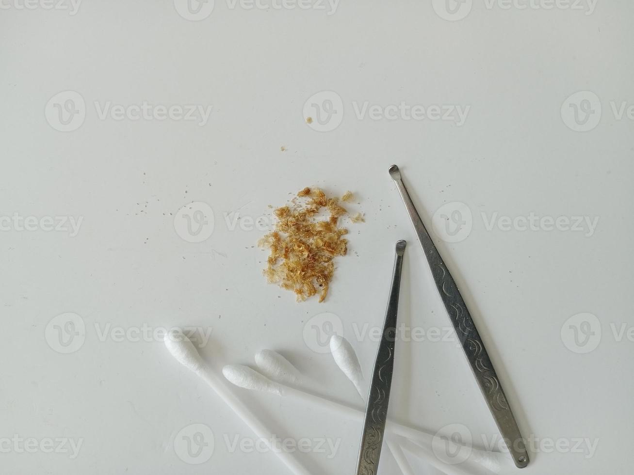 Closeup of Earwax and two ear pick tools and cotton swabs On the light blue table top photo