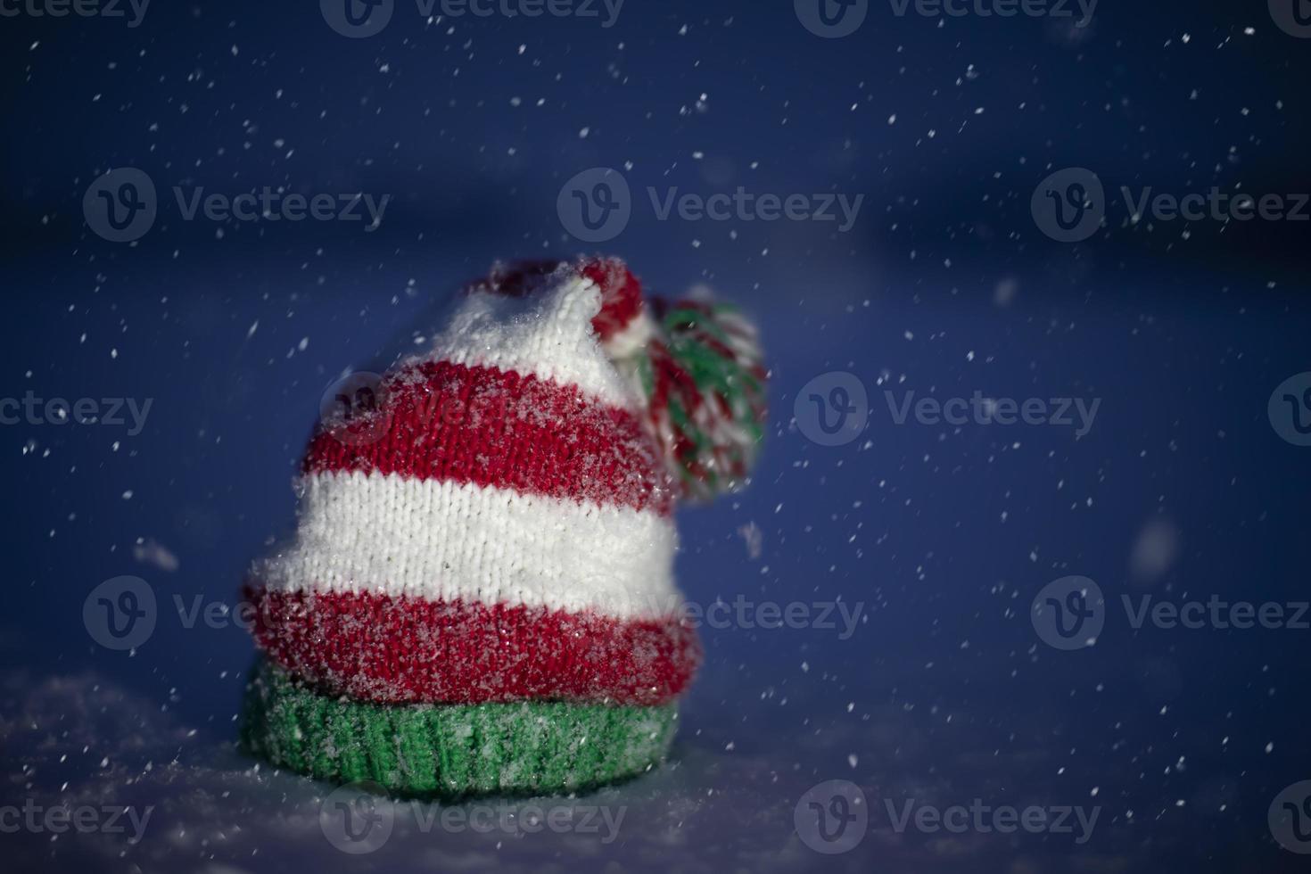 Knitted Christmas hat on a blue snowy background. Funny Christmas hat on snow background. photo